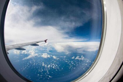 View from an airplane window of the wing above clouds and open ocean