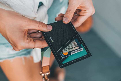 DIVEIN tester holds a Reborn Rubber recycled-wetsuit wallet while tucking away cash and a card