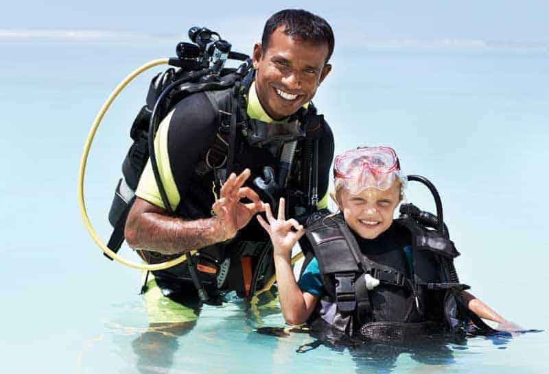 Dive instructor and a young diver giving the OK signal in shallow water