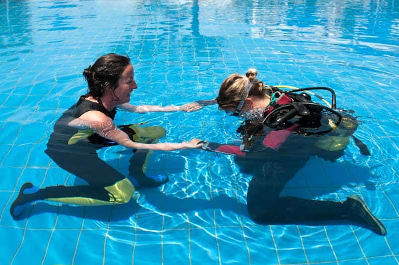 Instructor Teaching Pool Skills Instructor and student kneeling underwater in a pool, practicing a scuba skill together