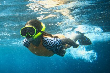 DIVEIN tester swimming just below the surface while breathing through a bright yellow mask and snorkel