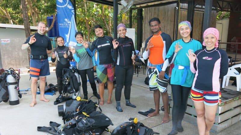 Divers in wetsuits giving the OK sign at a dive centre during a Green Fins trainer session
