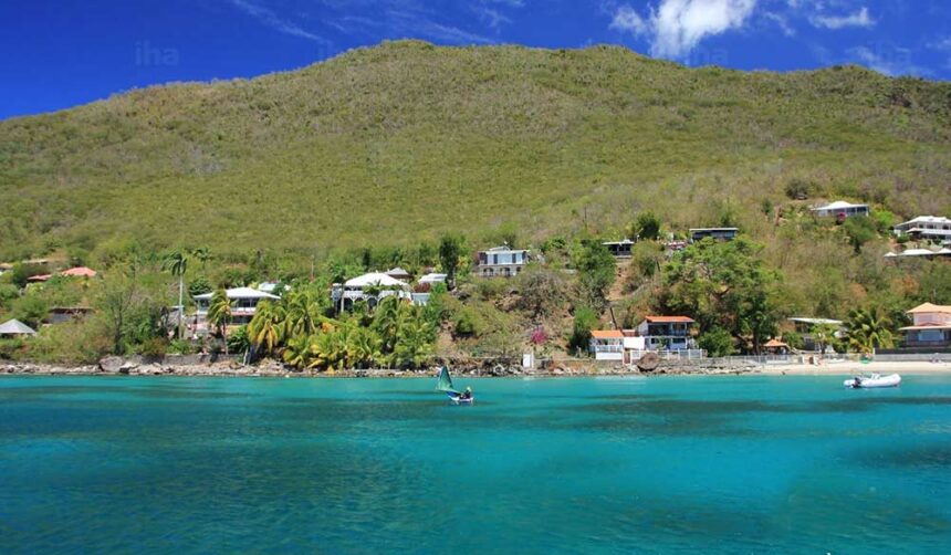 Green hillside and village above turquoise water on the Martinique coast at Belle Fontaine
