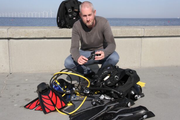 Our tester crouched beside a full scuba kit laid out on the quayside, holding the Zeagle F8 regulator