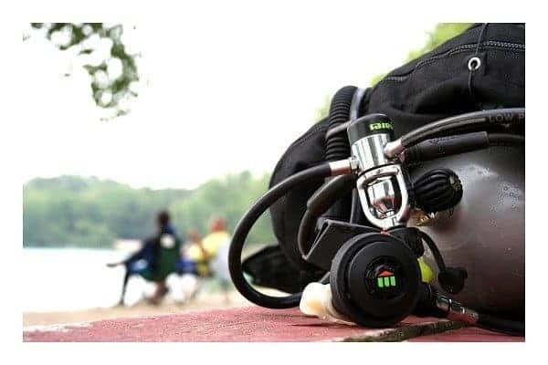 scuba tank and regulator with hoses resting on a table beside a lake