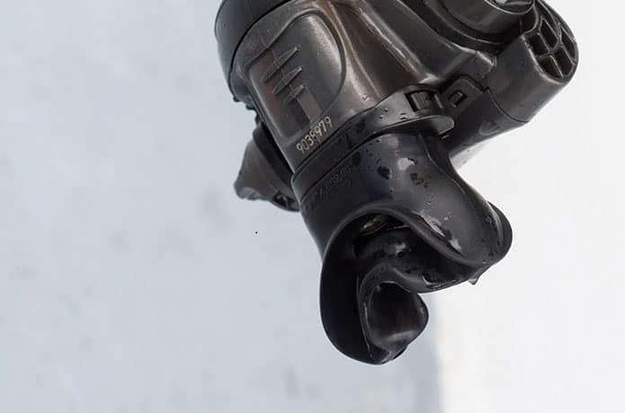Well-worn black regulator mouthpiece hanging loose and torn from its second stage