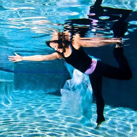 Cancer survivor striking a graceful underwater dance pose during a portrait session