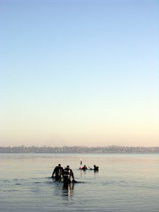 Divers wading into calm water for a shore dive at dusk