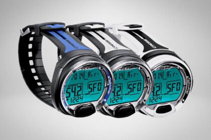 Three Cressi Leonardo dive computers in black, blue and white with backlit teal displays