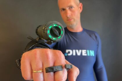 DIVEIN tester holding the Waydoo Subnado dive scooter to camera with its green light ring lit