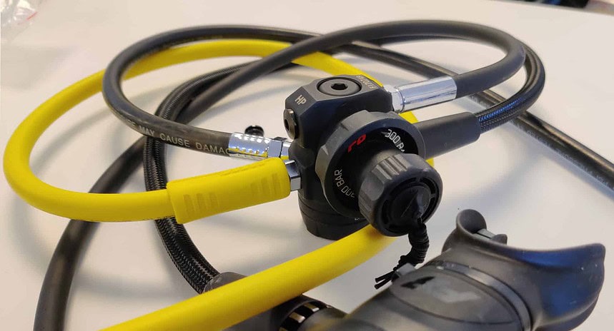 Zeagle F8 First Stage And Hoses Zeagle F8 regulator first stage with black and yellow hoses coiled on a white surface