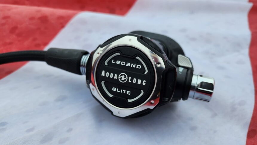 Aqualung Leg3nd Elite second stage with its chrome trimmed cover lying on a red and white cloth