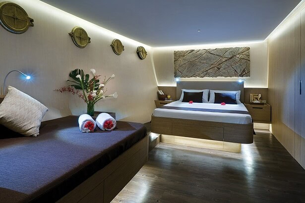 Spacious cabin aboard the Pelagian with a large bed, artwork and mood lighting
