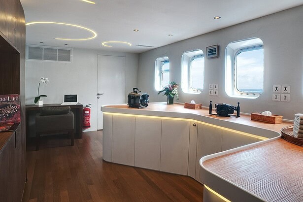 Camera room aboard the Pelagian liveaboard with a curved counter and laptop workstation
