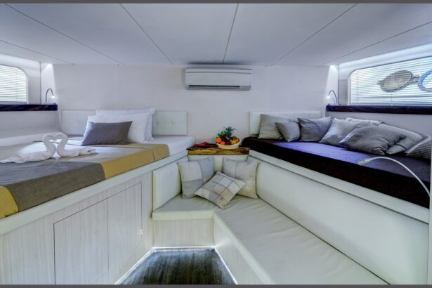 Deluxe cabin aboard the Pelagian with a made-up bed, fruit bowl, and cushioned bench seating