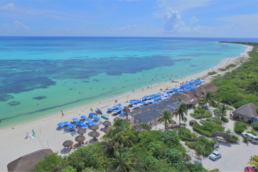 Punta Sur Beach Club Cozumel Aerial view of a Cozumel beach club with palapas and umbrellas beside turquoise reef water