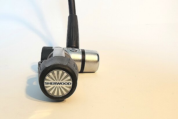 Sherwood Brut Pro first stage standing upright on its T shaped body with the hose attached