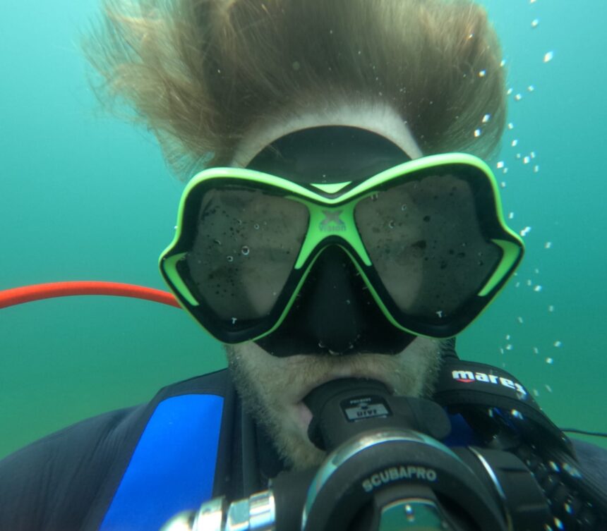 Close front view of our reviewer underwater in the green Mares X-Vision mask