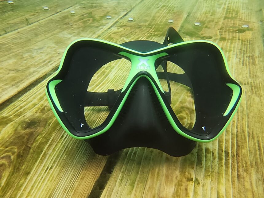 Mares X-Vision mask lying face up on submerged wooden planks in green water