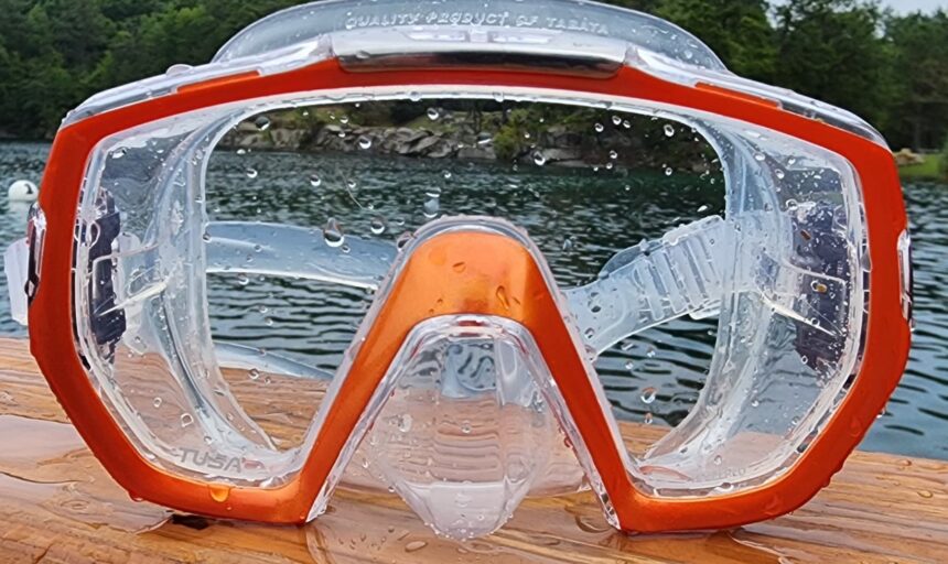 Water beaded across the wide clear lens of the TUSA Freedom Elite with a lake behind