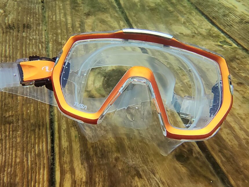 TUSA Freedom Elite mask resting on submerged wooden planks in green tinted water