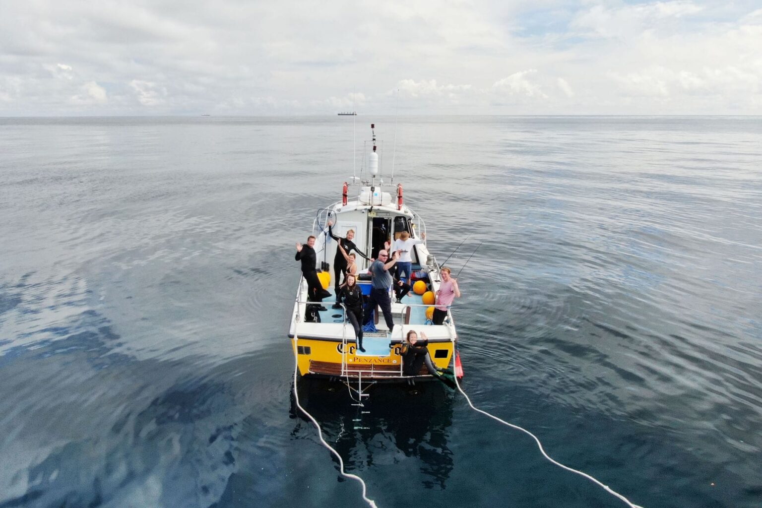 Group of snorkelers cheering aboard a small boat off Penzance