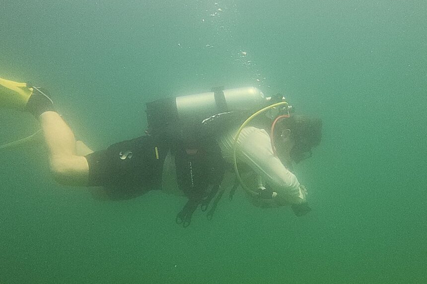 Our tester holding horizontal trim in murky quarry water wearing the Atomic Aquatics BC2