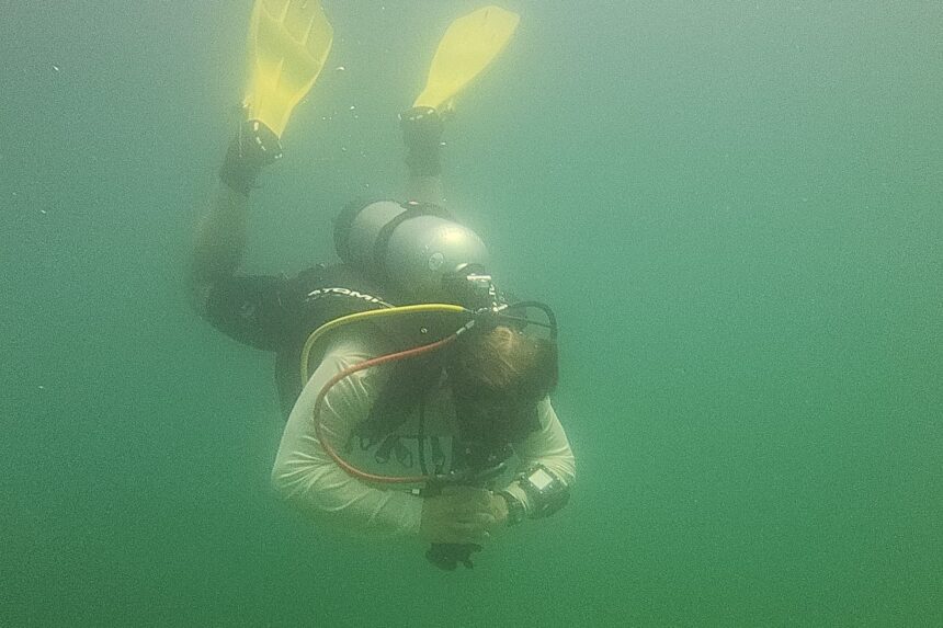 DIVEIN tester descending head down in green quarry water while testing the Atomic Aquatics BC2