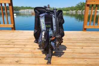 Oceanic Biolite BCD in blue and black standing on a wooden dock beside the quarry lake test site