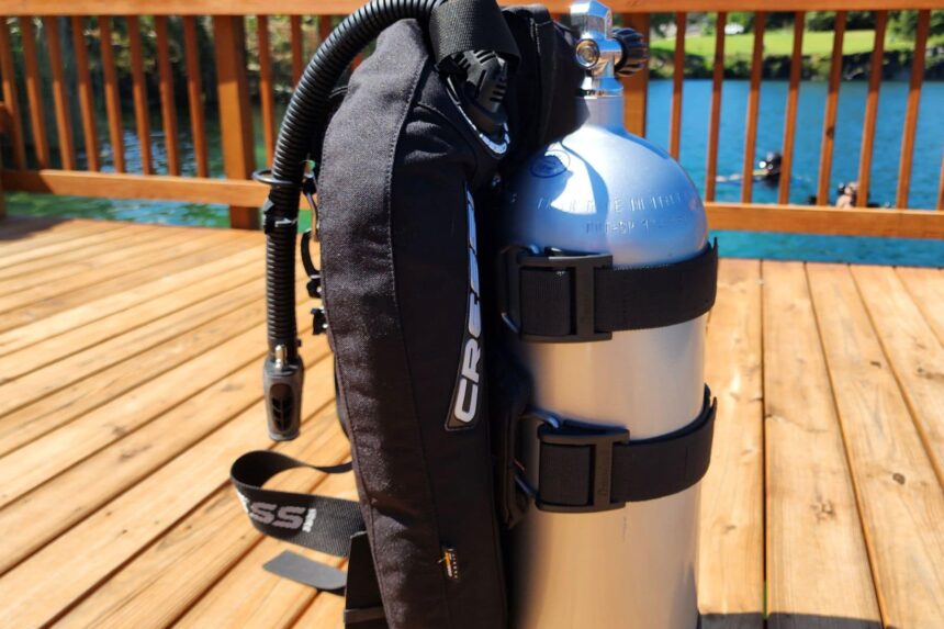 Two cam bands holding an aluminum tank against the Cressi Aquawing wing on a sunlit dock