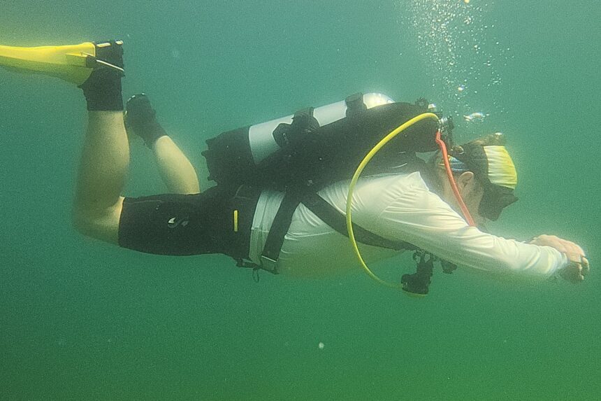 DIVEIN reviewer finning through green freshwater wearing the Cressi Aquawing and a single tank