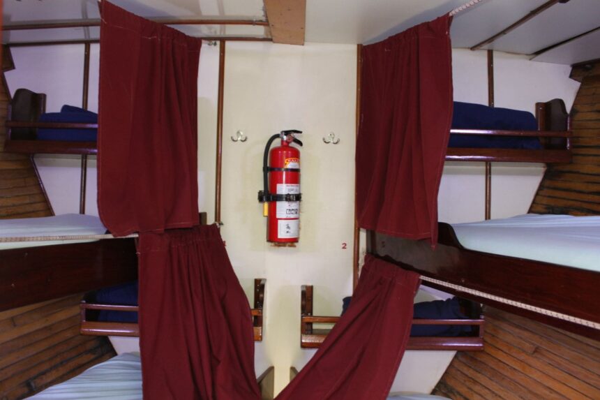 Curtained bunk berths below deck on the Sea Explorer, with a fire extinguisher mounted on the wall