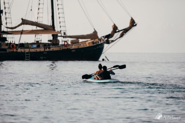 couple kayaking near the anchored Adelaar sailing yacht at dusk