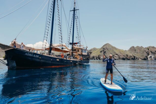 man paddleboarding near the anchored Adelaar sailing yacht