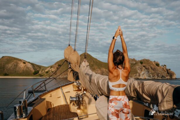 woman stretching into a yoga pose on the Adelaar's bow at sunset