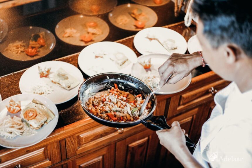 chef plating a seafood stir fry alongside rows of appetizer dishes