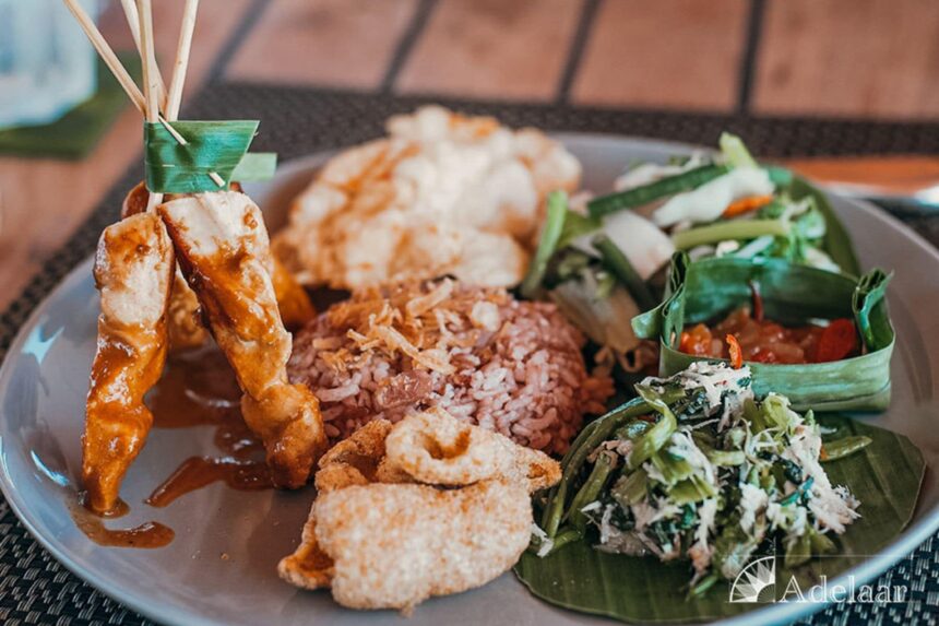Indonesian rice plate with satay skewers, crackers and vegetable salads