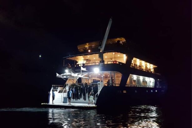 Infiniti liveaboard lit up at night with divers gathered on the dive deck