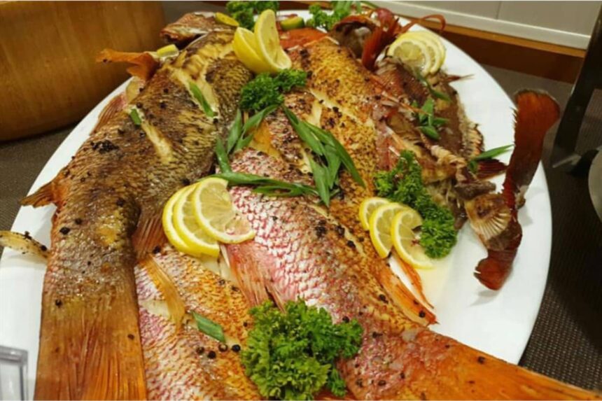 platter of grilled whole fish garnished with lemon and parsley