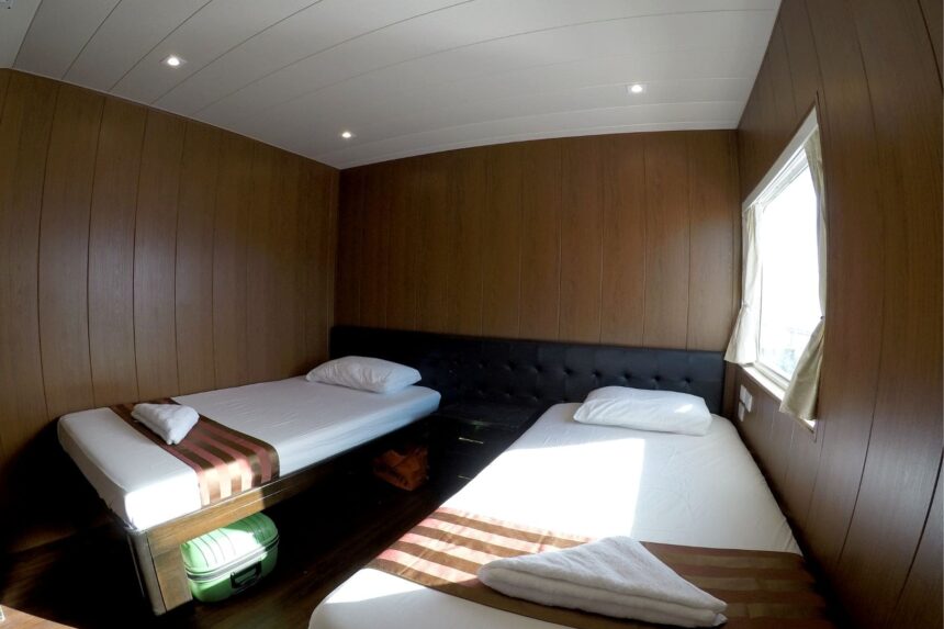 Twin single beds in a wood paneled cabin aboard the Infiniti liveaboard