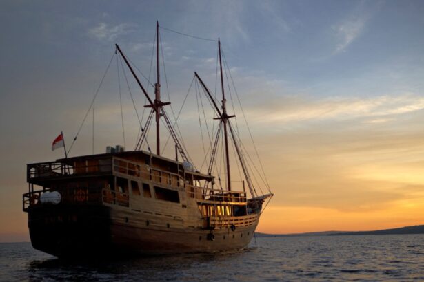 Damai I traditional phinisi liveaboard anchored at sea under a sunset sky