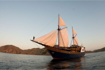 Damai I liveaboard phinisi schooner at anchor with masts rigged and flags flying