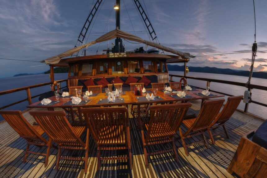 Outdoor dining table set on the Damai I's deck at dusk