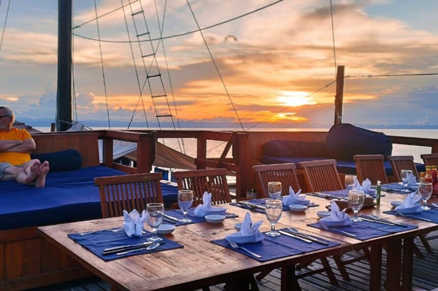 Guest relaxing on cushions beside the sunset dining table aboard the Damai I