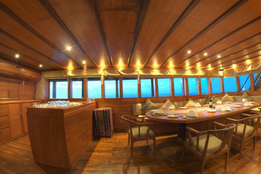Long dining table set for a shipboard dinner in the Damai II's wood-paneled indoor salon