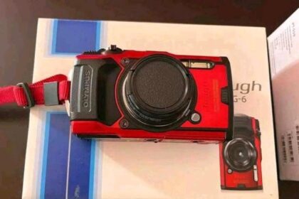 Our review unit of the Olympus Tough TG-6 sitting on its box with the lens cap fitted and wrist strap attached