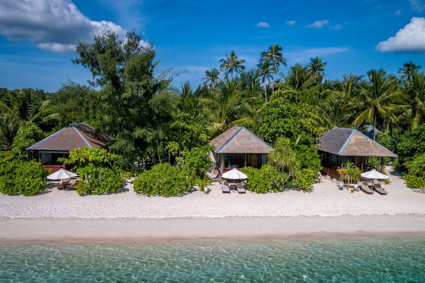 thatched-roof beach bungalows fronting a white sand beach at Wakatobi Resort
