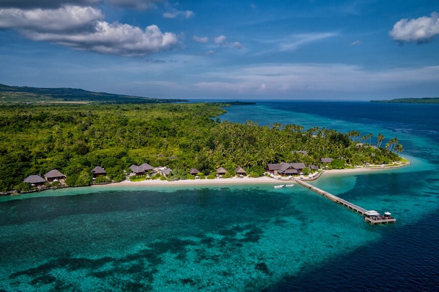 Aerial view of Wakatobi Resort's overwater jetty and reef-lined coastline in Indonesia