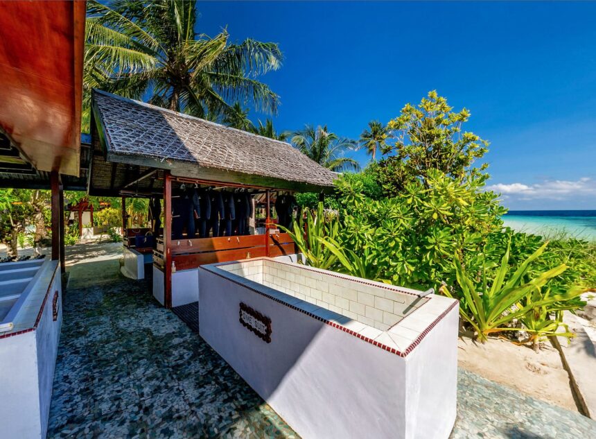 wetsuits and gear hanging at Wakatobi's beachside dive center rinse station