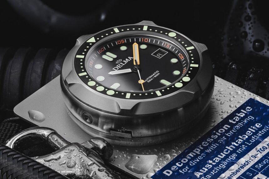Delma Quattro Beside A Decompression Table Delma Quattro dive watch standing upright beside a printed decompression table